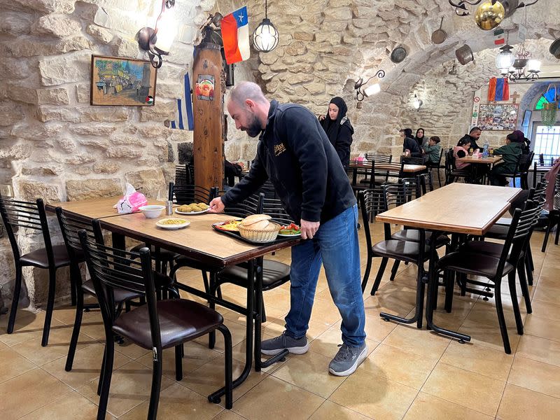 Ala'a Salameh, de 42 años, cuarta generación de copropietarios del restaurante Afteem, coloca comida en una mesa del interior del restaurante de Belén, en Cisjordania