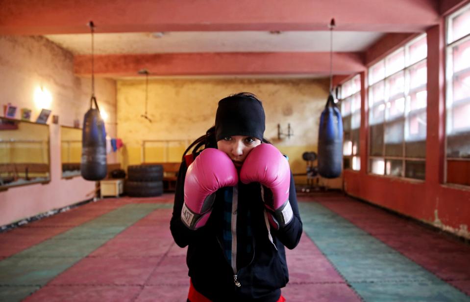 In this Wednesday, March, 5, 2014 photo, an Afghan female boxer pauses during a practice session at the Kabul Stadium boxing club. The Afghanistan National Olympic Committee boxing club has fewer than a dozen women and little money for them. Previously nongovernmental organizations supported them. At that time there were 25 young women who received a salary the equivalent of $100 per month and transportation to and from the Kabul Stadium where they train. (AP Photo/Massoud Hossaini)