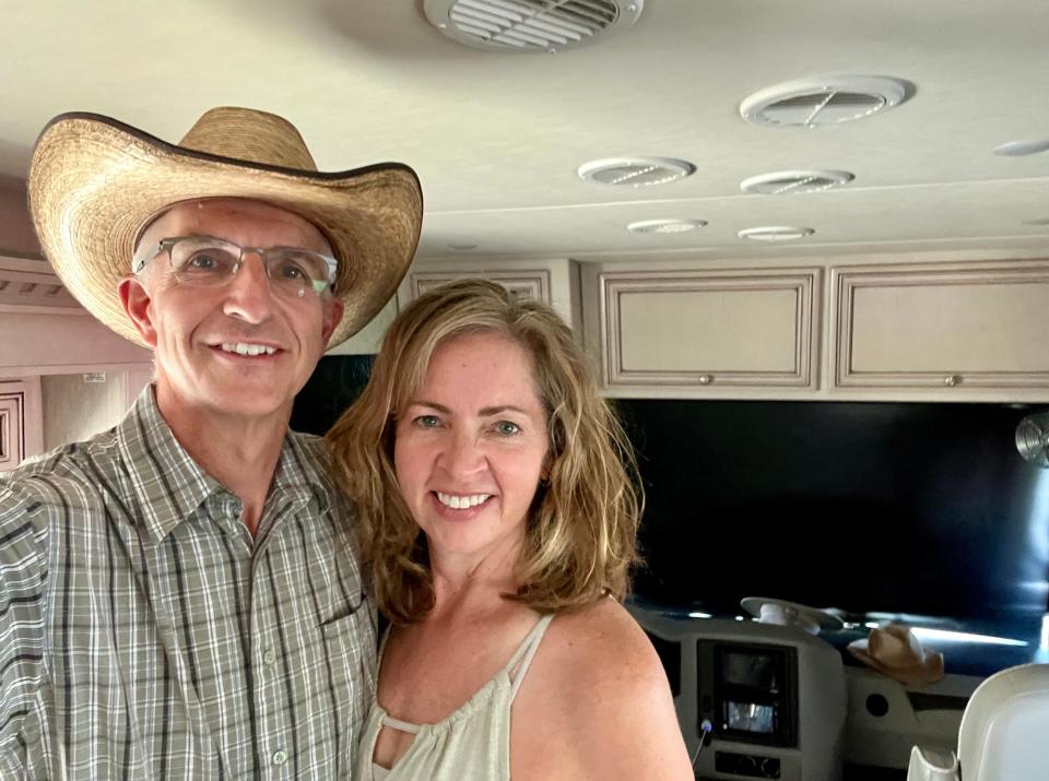 A man in cowboy hat with woman with blonde hair smiling inside of a motorhome at night