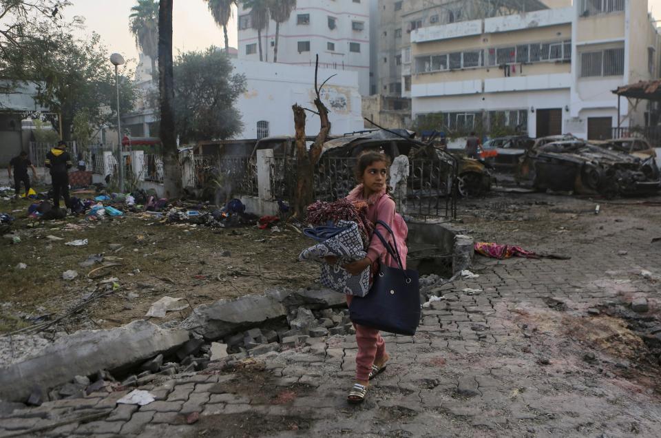 A girl carries blankets as she walks past the site of a deadly explosion at al-Ahli Hospital in Gaza City on Wednesday (Copyright 2023 The Associated Press. All rights reserved.)