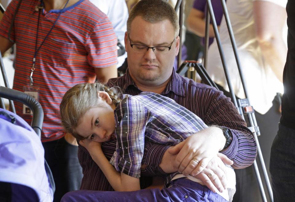 Marshall Christensen, of Provo, holds his daughter Jessica, 13, as they wait for the H.B 105 bill signing ceremony at the Utah State Capitol, Tuesday, March 25, 2014, in Salt Lake City. Parents of Utah children with severe epilepsy are cheering a new state law that allows them to obtain a marijuana extract they say helps with seizures, but procuring it involves navigating a thorny set of state and federal laws. Utah's Republican Gov. Gary Herbert has already approved the law and held the signing ceremony Tuesday afternoon. The new law doesn't allow medical marijuana production in Utah but allows families meeting certain restrictions to obtain the extract from other states. (AP Photo/Rick Bowmer)