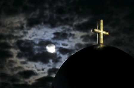 The moon rises above a church on the Greek island of Santorini, Greece, July 1, 2015. REUTERS/Cathal McNaughton