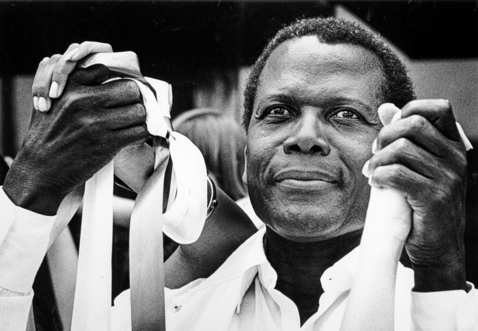 Sidney Poitier holds hands with others