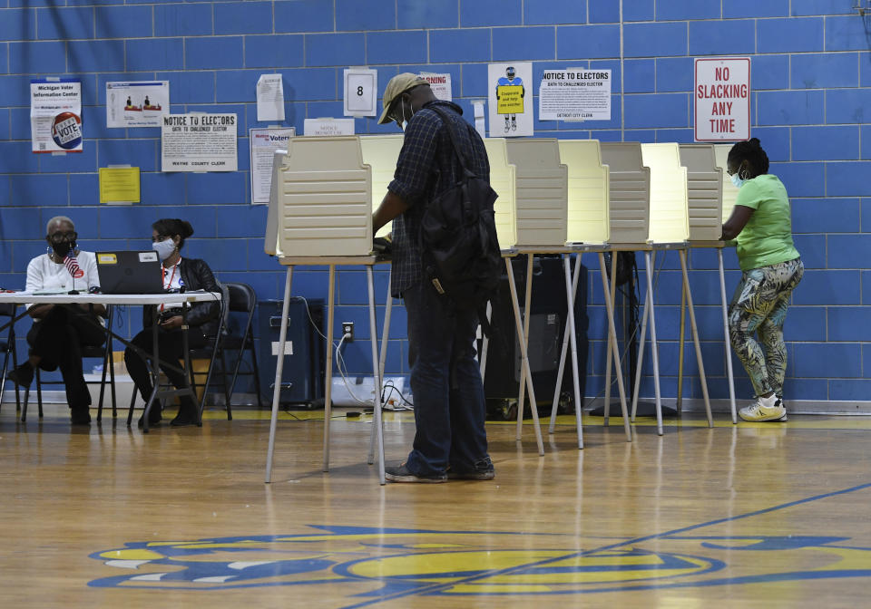 Voters cast ballots in a school gym.