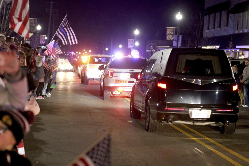 People line the street for a procession from a Rockford, Ill., hospital to the funeral home in Huntley, Ill., on Friday evening, March 8, 2019, for fallen McHenry County Sheriff's Deputy Jacob Keltner. An Illinois man faces federal murder charges in the shooting death of the sheriff's deputy that led to an hourslong standoff with police along an interstate. (Patrick Kunzer/Daily Herald via AP)