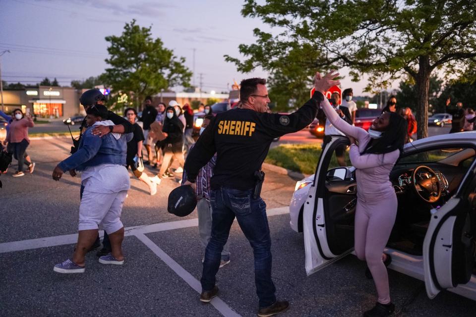 Genesee County Sheriff Chris Swanson high-fives a woman who called his name as he marched with protesters in memory of George Floyd on May 30 in Flint Township, Mich.