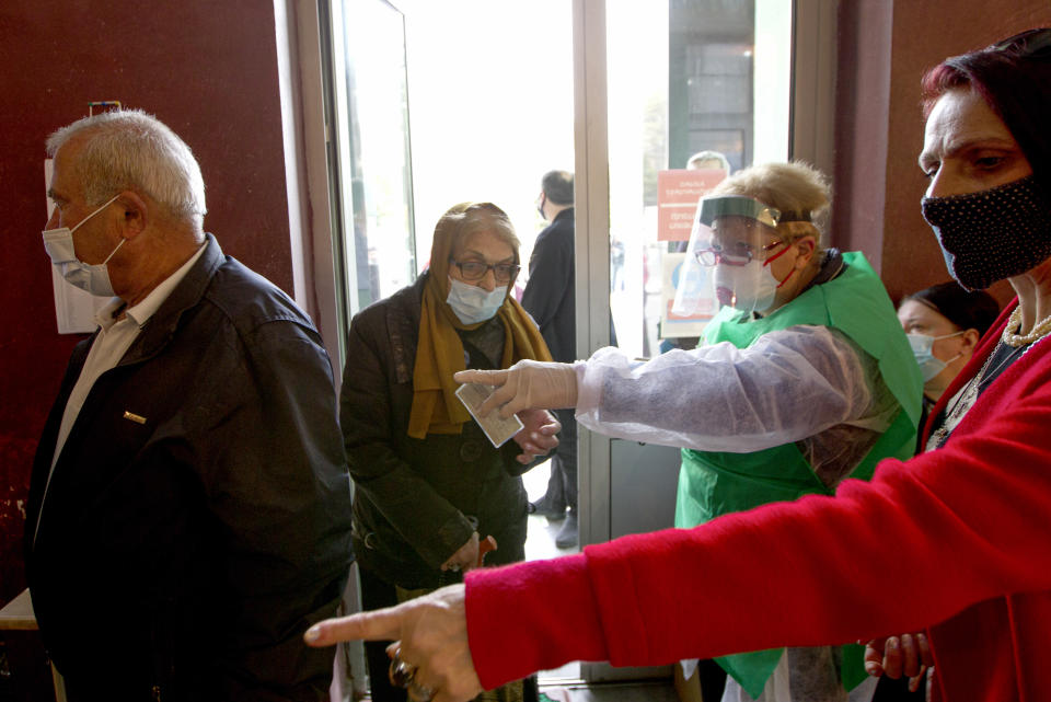 A woman wearing a face mask to help curb the spread of the coronavirus, enter a polling station to vote during the parliamentary elections in Tbilisi, Georgia, Saturday, Oct. 31, 2020. The hotly contested election between the Georgian Dream party, created by billionaire Bidzina Ivanishvili who made his fortune in Russia and has held a strong majority in parliament for eight years, and an alliance around the country's ex-President Mikheil Saakashvili, who is in self-imposed exile in Ukraine. (AP Photo/Shakh Aivazov)