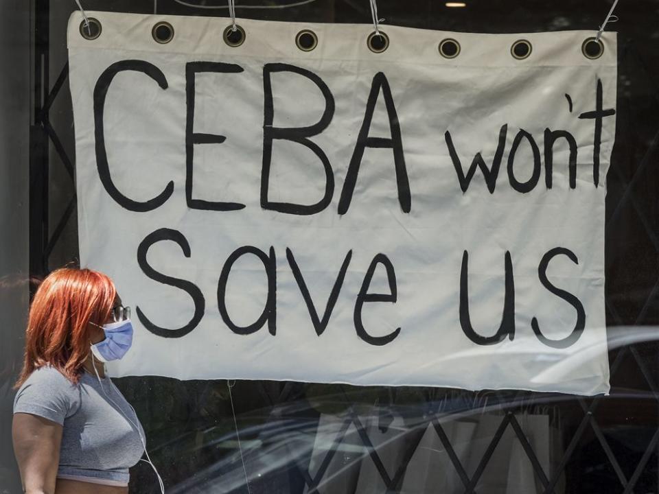  A pedestrian walks past a store on Toronto’s Dundas Street West stating ‘CEBA Won’t Help Us’ during the COVID-19 pandemic, 2020.
