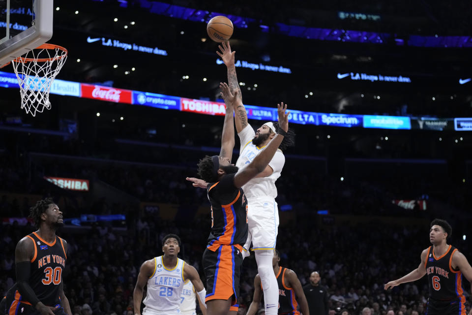 Los Angeles Lakers forward Anthony Davis, center right, shoots over New York Knicks center Mitchell Robinson during the first half of an NBA basketball game Sunday, March 12, 2023, in Los Angeles. (AP Photo/Marcio Jose Sanchez)