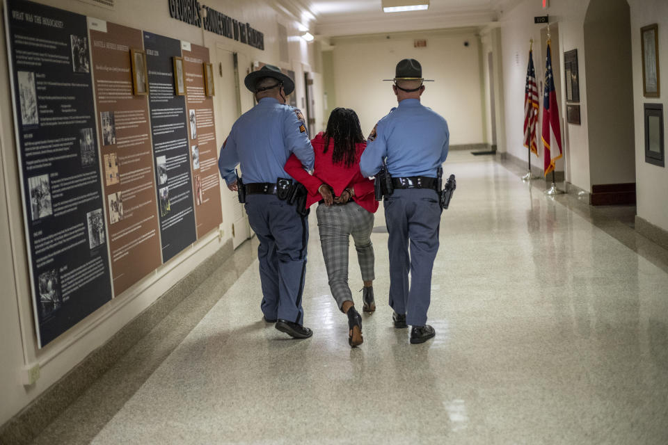 Rep. Park Cannon (D-Atlanta) is escorted out of the Georgia Capitol by Georgia state troopers after being asked to stop knocking on a door that lead to Gov. Brian Kemp’s office while Kemp was speaking after signing a sweeping overhaul of state elections behind closed doors in Atlanta, Thursday, March 25, 2021. An attorney for Cannon says it’s “law enforcement overreach” to charge the Georgia House member with two felonies. (Alyssa Pointer/Atlanta Journal-Constitution via AP)