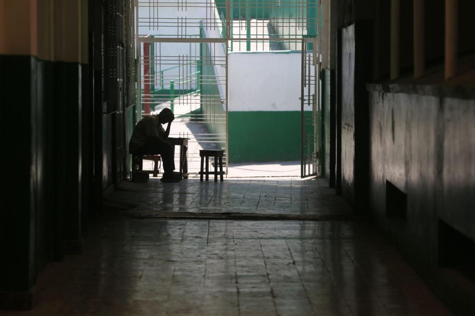 Hombre sentado al costado de una puerta del hospital.