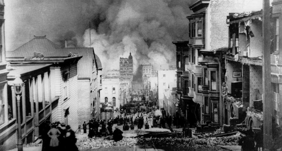 People watch smoke billowing from fires on a quake-damaged street