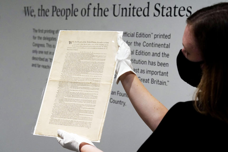 Ella Hall, a specialist in Books and Manuscripts at Sotheby's, in New York, holds a 1787 printed copy of the U.S. Constitution, Friday, Sept. 17, 2021. Sotheby's announced Friday — appropriately on Constitution Day — that in November it will put up for auction one of just 11 surviving copies of the Constitution from the official first printing produced for the delegates to the Constitutional Convention and for the Continental Congress. It's the only copy that remains in private hands and has an estimate of $15 million-$20 million. (AP Photo/Richard Drew)