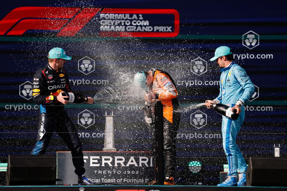 May 5, 2024; Miami Gardens, Florida, USA; Red Bull Racing driver Max Verstappen (left) and Ferrari driver Charles Leclerc (right) spray champagne on race winner McLaren driver Lando Norris (4) during the Miami Grand Prix at Miami International Autodrome. Mandatory Credit: Peter Casey-USA TODAY Sports
