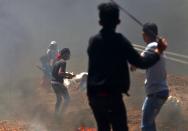 <p>Palestinian children use slingshots during clashes with Israeli forces near the border between Israel and the Gaza Strip on May 14, 2018. (Photo: Mohammed Abed/AFP/Getty Images) </p>