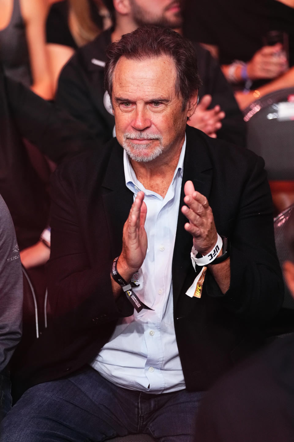 Dennis Miller in a suit clapping in an audience