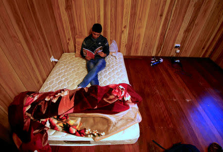 Ali Rasooli, a refugee from Afghanistan, sits on his mattress reading a book in a house he rents with other refugees, in the western Sydney suburb of Guildford, Australia, July 17, 2016. REUTERS/David Gray