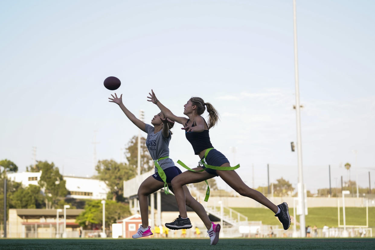 FILE - Syndel Murillo, 16, left, and Shale Harris, 15, reach for a pass as they try out for the Redondo Union High School girls flag football team on Thursday, Sept. 1, 2022, in Redondo Beach, Calif. California officials are expected to vote Friday on the proposal to make flag football a girls' high school sport for the 2023-24 school year. (AP Photo/Ashley Landis, File )