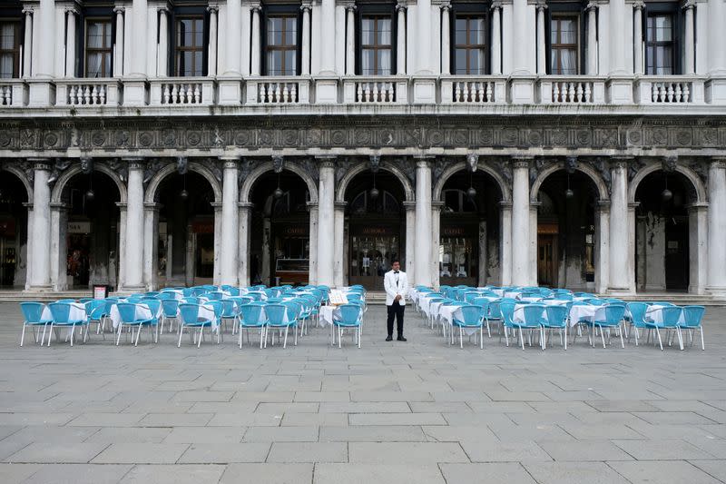 FILE PHOTO: A waiter stands by empty tables outside a restaurant at St Mark's Square, which is usually full of tourists, after Italy's government adopted a decree with emergency new measures to contain the coronavirus, in Venice