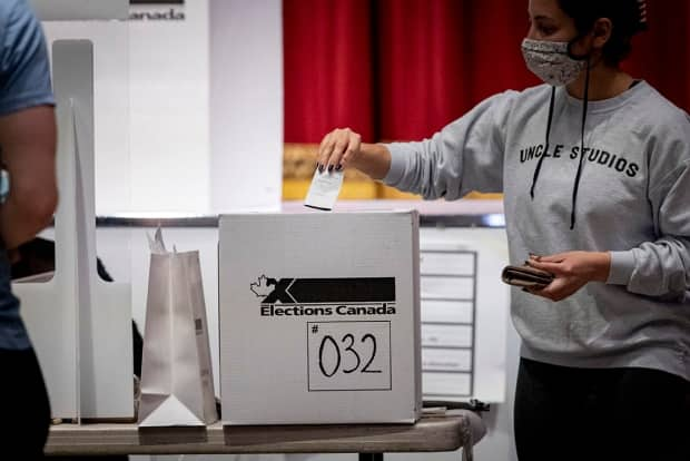 A voter, seen in this image taken from the door of a polling station, casts a ballot in Toronto's University-Rosedale riding on Sept. 20, 2021.  (Evan Mitsui/CBC - image credit)