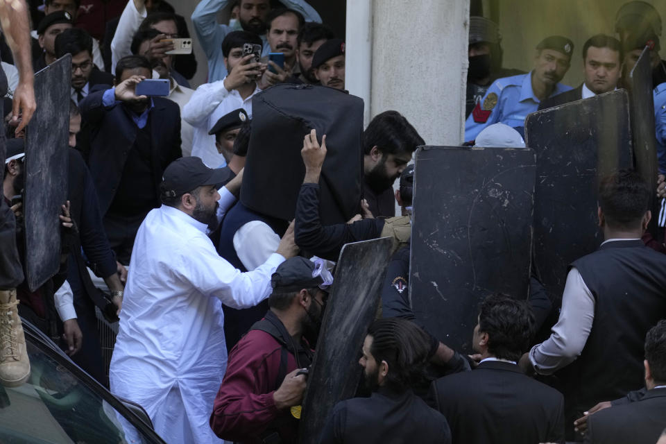 Security personnel with bulletproof shields escort former Prime Minister Imran Khan, center, as he arrives to appear in a court, in Islamabad, Pakistan, Monday, March 27, 2023. A Pakistani court ruled in defense of former Prime Minister Khan, granting him protection from arrest as lawsuits mounted against the ousted premier, with police charging him with incitement to violence in several cases when his followers clashed with the security forces this month. (AP Photo/Anjum Naveed)