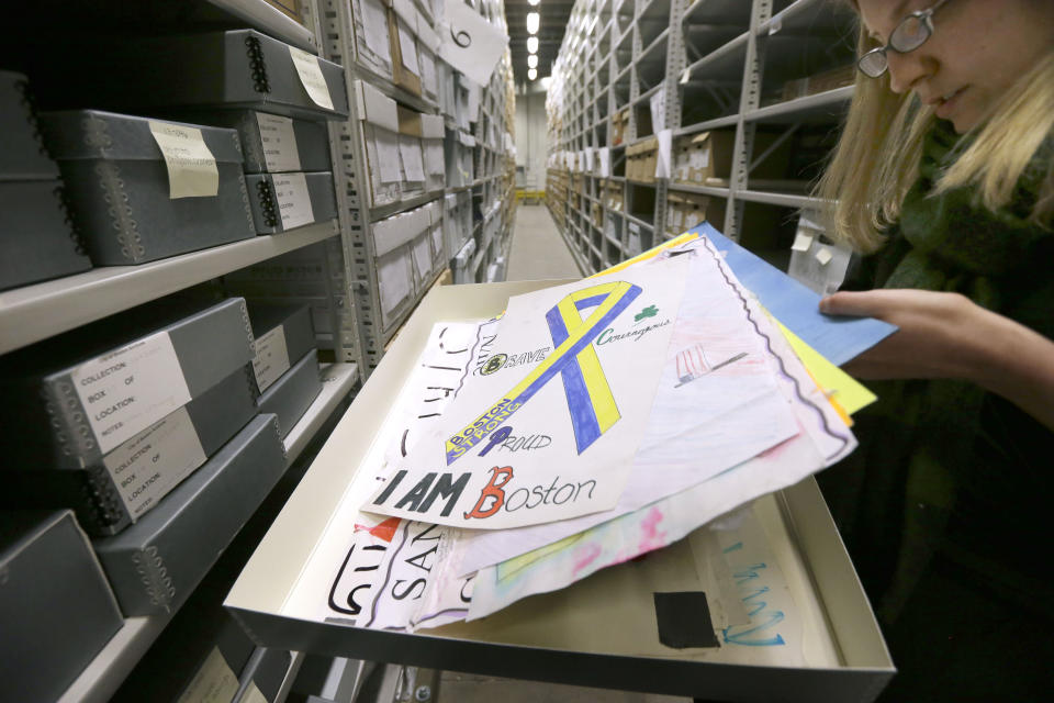 In this March 26, 2014 photo, archivist Marta Crilly for the city of Boston, displays placards that were part of the memorial near the finish line of the Boston Marathon at the city archives in Boston. Thousands of items from the original memorial for marathon bombing victims are going on display at the Boston Public Library in April to mark the anniversary of the attacks. (AP Photo/Steven Senne)