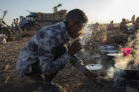 A Tigray refugee man who fled the conflict in the Ethiopia's Tigray lights his cigarette from wood fire at Hamdeyat Transition Center near the Sudan-Ethiopia border, eastern Sudan, Thursday, Dec. 3, 2020. Ethiopian forces on Thursday blocked people from the country's embattled Tigray region from crossing into Sudan at the busiest crossing point for refugees, Sudanese forces said.(AP Photo/Nariman El-Mofty)