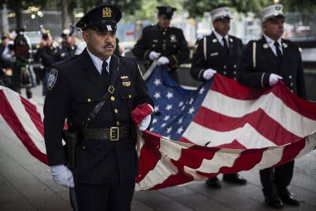 Members of the New York Police Department, Fire Department of New York and Port Authority Police Department carry an American flag at the beginning of the memorial observances held at the site of the World Trade Center in New York, September 11, 2014. REUTERS/Andrew Burton/POOL