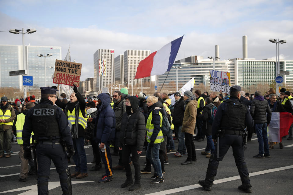 Yellow vests protesters holding a French flag march in Paris, Saturday, Dec. 7, 2019. A few thousand yellow vest protesters marched Saturday from the Finance Ministry building on the Seine River through southeast Paris, pushing their year-old demands for economic justice and adding the retirement reform to their list of grievances. (AP Photo/Francois Mori)