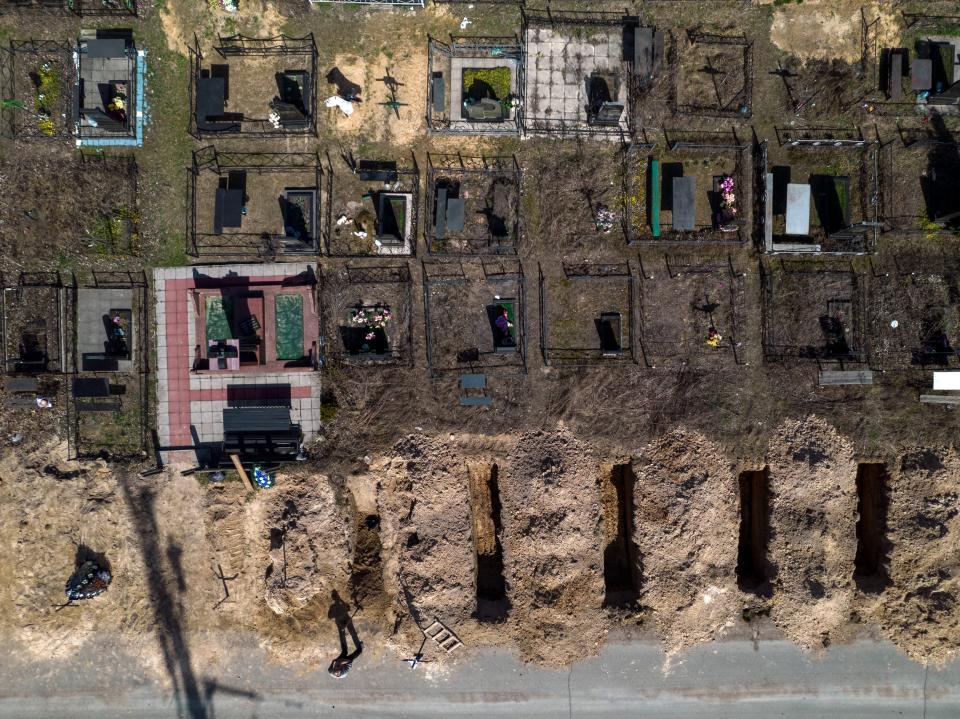 A man takes a break from working on the graves of civilians killed in the Ukrainian town of Bucha during the war with Russia on April 14, 2022.