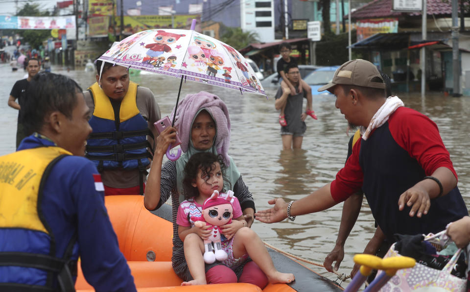 Rescue team talks to a girl through floodwaters at Jatibening on the outskirt of Jakarta, Indonesia, Wednesday, Jan. 1, 2020. Severe flooding hit Indonesia's capital just after residents celebrating New Year's Eve, forcing a closure of an airport and thousands of inhabitants to flee their flooded homes. (AP Photo/Achmad Ibrahim)