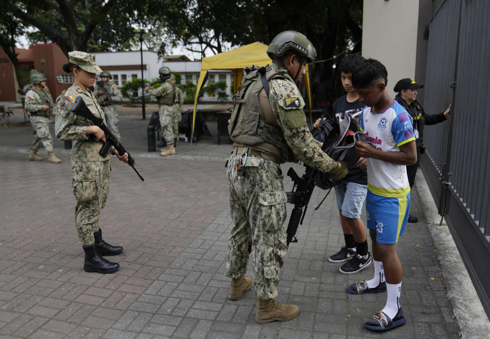 Soldados registran mochilas de estudiantes en terrenos escolares en el centro de Guayaquil, Ecuador, el viernes 18 de agosto de 2023. Los ecuatorianos elegirán un nuevo presidente el domingo, menos de dos semanas después de que el país sudamericano se viera sacudido por el asesinato de uno de los candidatos. (AP Foto/Martín Mejía)