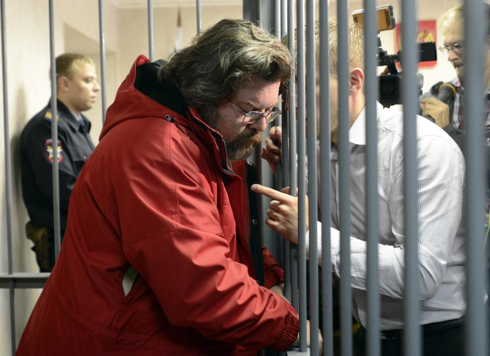 Greenpeace International spokesperson Roman Dolgov speaks to an unidentified man from inside a defendants' box at a district court building in Murmansk