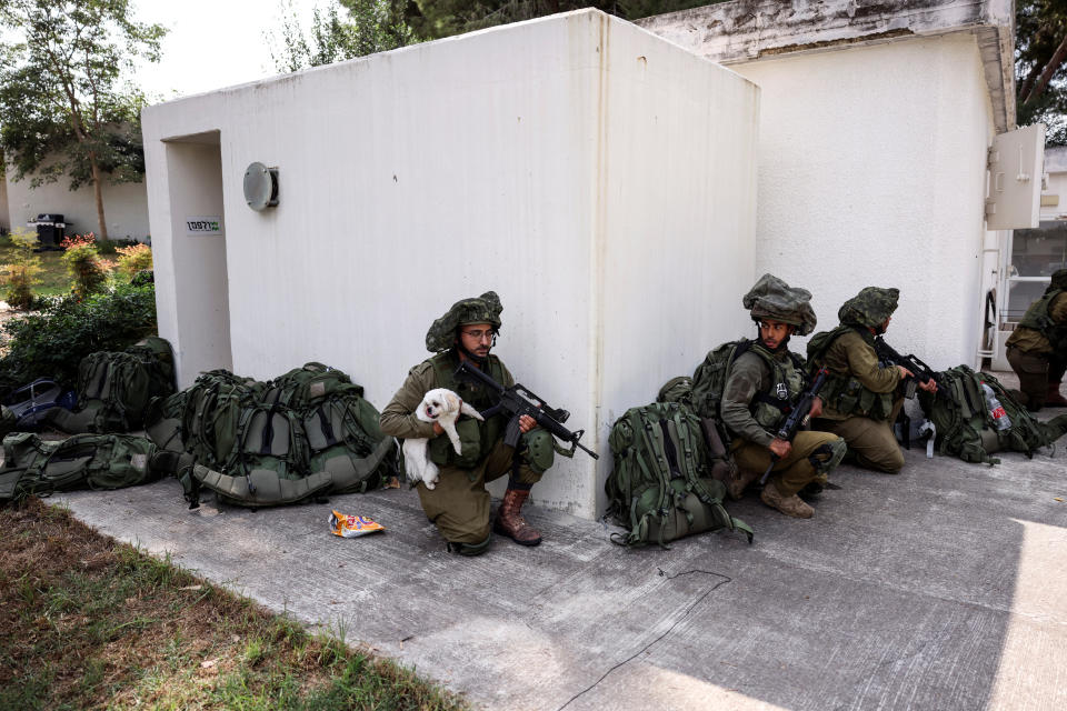 An Israeli soldier holds a rescued dog as he takes position near a bomb shelter in Kibbutz Kfar Aza, in southern Israel, October 10, 2023. REUTERS/Ronen Zvulun