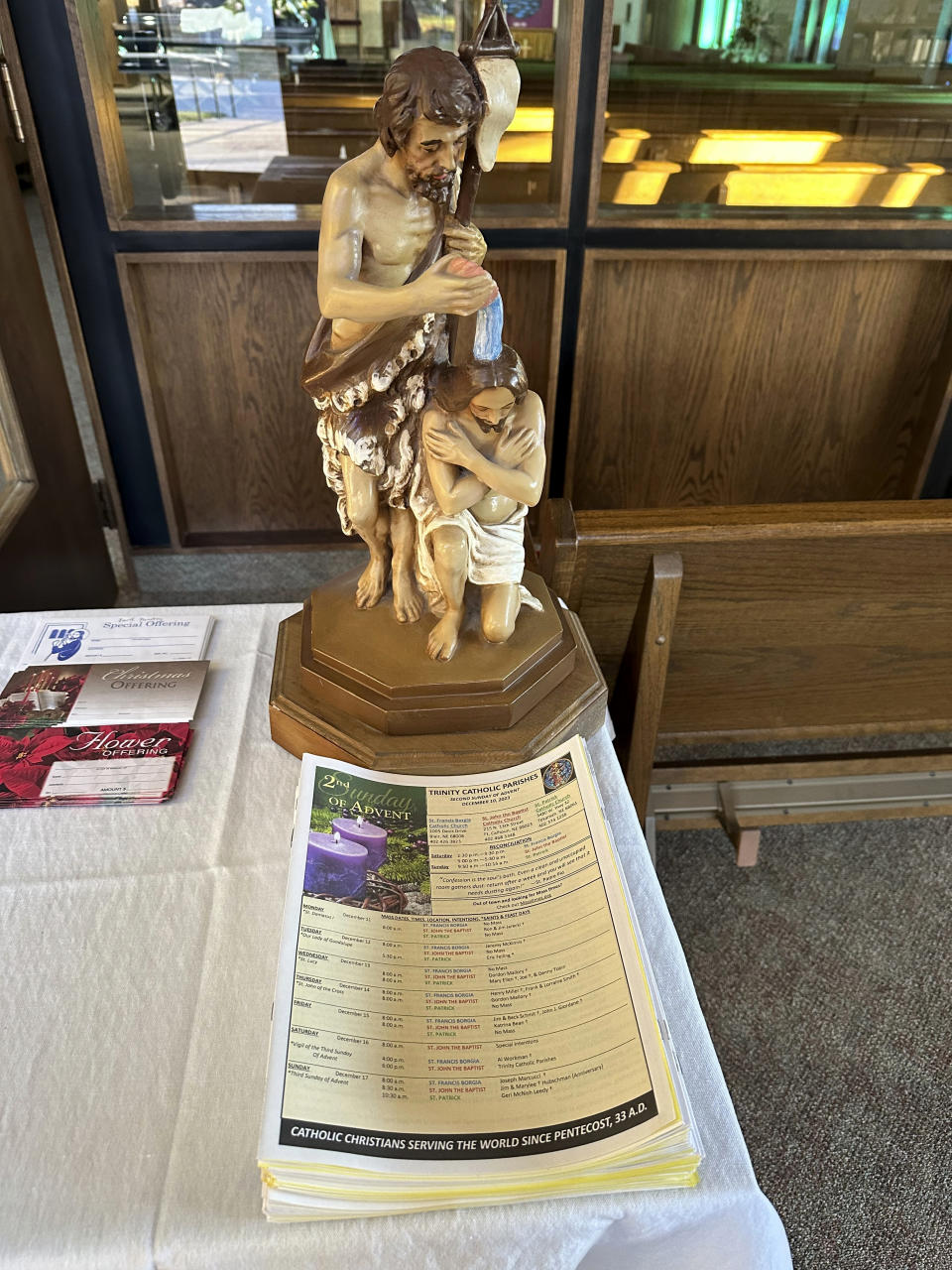 A stack of unused bulletins sits inside St. John the Baptist Catholic Church in Fort Calhoun, Neb., Monday, Dec. 11, 2023. Services were cancelled at the church Sunday after the parish's priest was fatally stabbed during a break-in at the rectory where he lived next door. (AP Photo/Josh Funk)