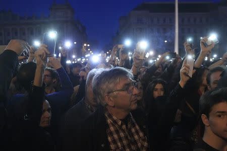 People light with their mobile phones as they protest against the bill that would undermine Central European University, a liberal graduate school of social sciences founded by U.S. financier George Soros in Budapest, Hungary, April 9, 2017. REUTERS/Bernadett Szabo