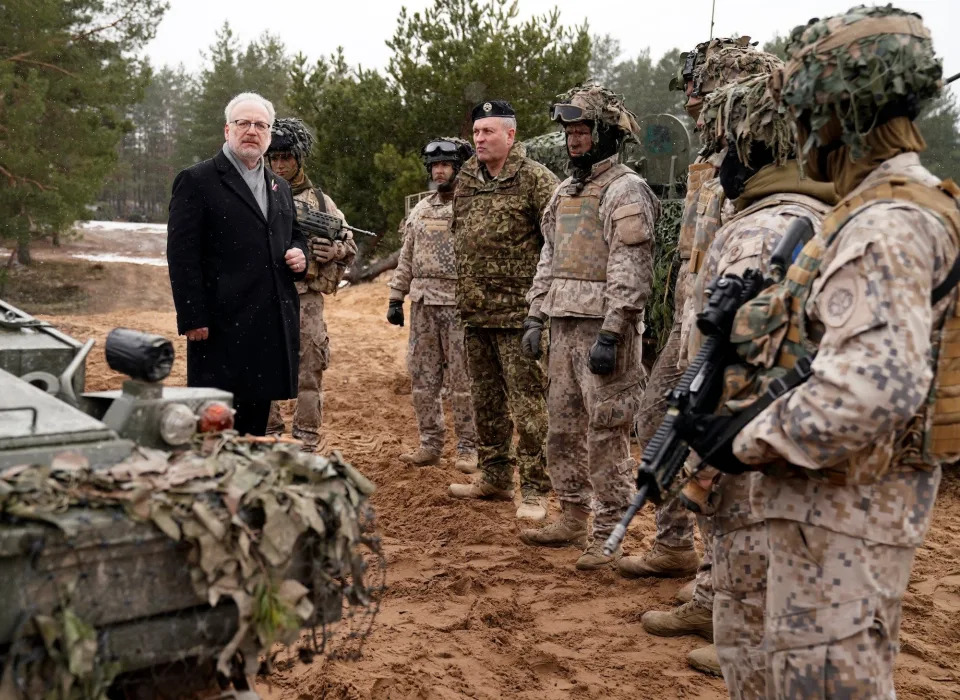 Latvian President Egils Levits speaks to Latvian troops in camouflage gear