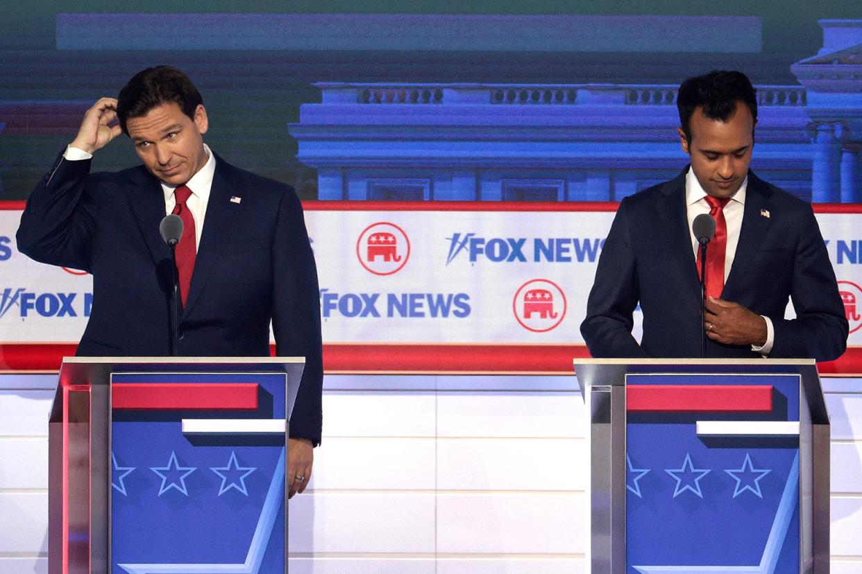Ron DeSantis scratches his head on the Fox News debate stage while Vivek Ramaswamy looks down.