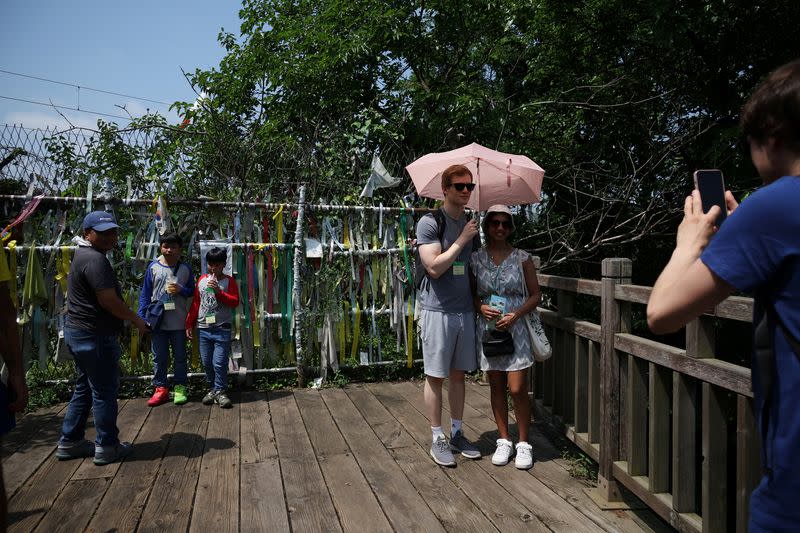 Foreign tourists participating in DMZ tour pose for photographs in front of a military fence near the demilitarized zone separating the two Koreas, in Paju