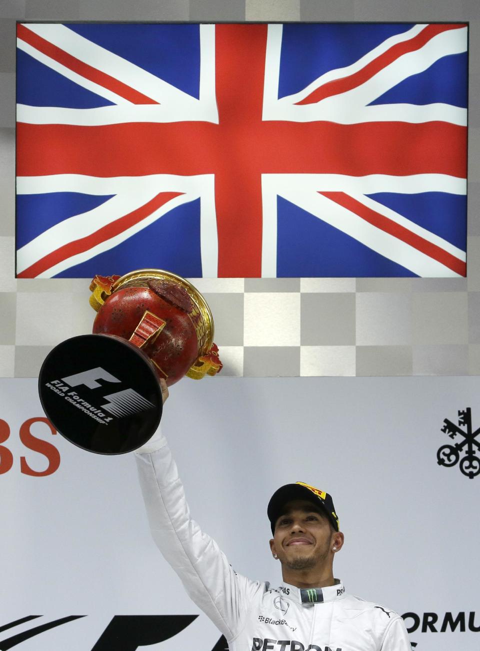 El británico Lewis Hamilton, de Mercedes, levanta en el podio el trofeo de ganador de la carrera del Gran Premio de Formula Uno en el Circuito Internacional de Shanghai, el domingo 20 de abril de 2014. (AP Foto/Alexander F. Yuan)