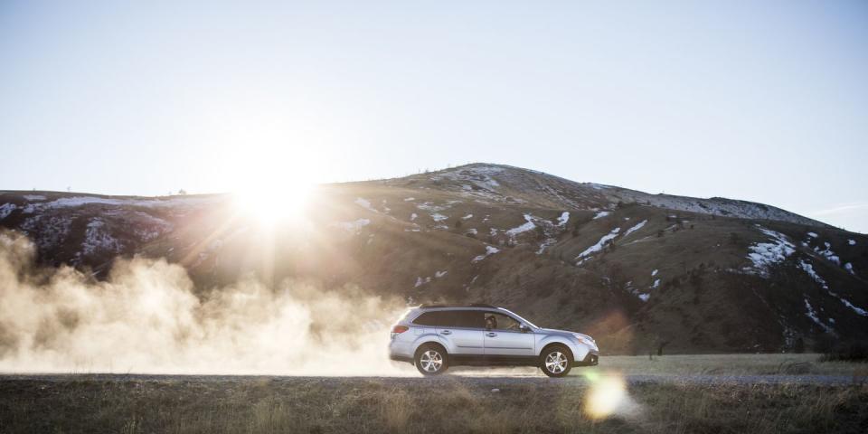 car kicking up dust on dirt road