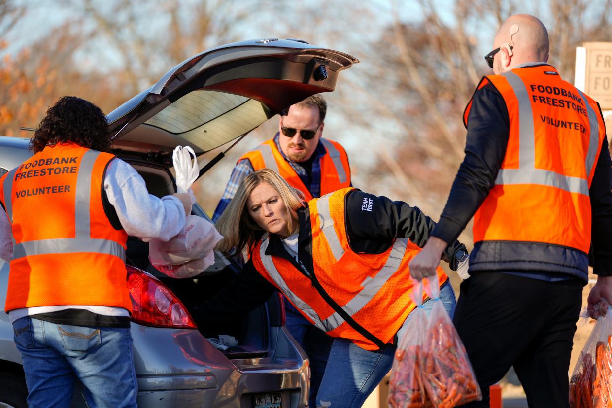 Freestore Foodbank volunteers place groceries into a patron’s car during the drive-through Holiday Meal Distribution put on by Freestone Foodbank along with Reds Youth Academy on Thursday, Nov. 16, 2023, at P&G MLB Cincinnati Reds Youth Academy in Roselawn.