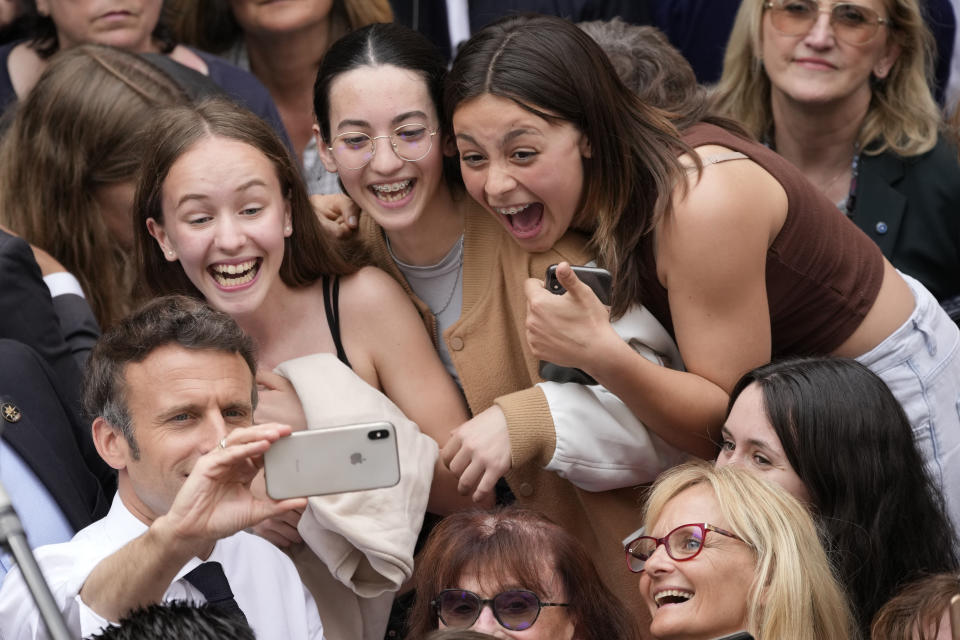 Centrist candidate and French President Emmanuel Macron makes a selfie with young residents after a campaign rally Friday, April 22, 2022 in Figeac, southwestern France. Emmanuel Macron is facing off against far-right challenger Marine Le Pen in France's April 24 presidential runoff. (AP Photo/Christophe Ena)