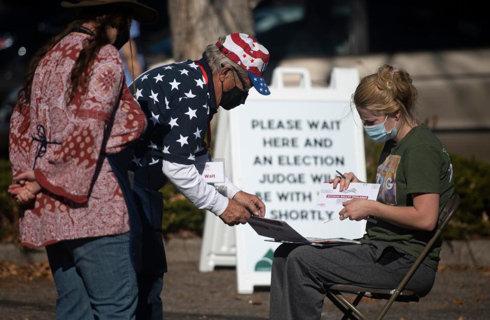 Election judges work with a voter to complete her ballot at the drive-thru ballot drop off location across from the Larimer County Courthouse in Fort Collins on Nov. 3, 2020.