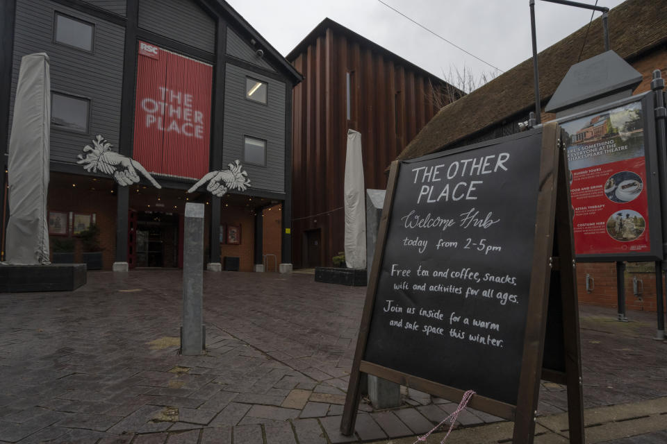 A notice board for warm hubs is displayed outside the Other Place theater, in Stratford-upon-Avon, Warwickshire, England, Tuesday, Feb. 28, 2023. The foyer of the Other Place theater in Shakespeare's birthplace of Stratford-upon-Avon is a cozy refuge from winter. One day a week the theater becomes a "warm hub," set up by the Royal Shakespeare Company to welcome people who may be struggling to heat their homes because of sky-high energy prices. (AP Photo/Kin Cheung)