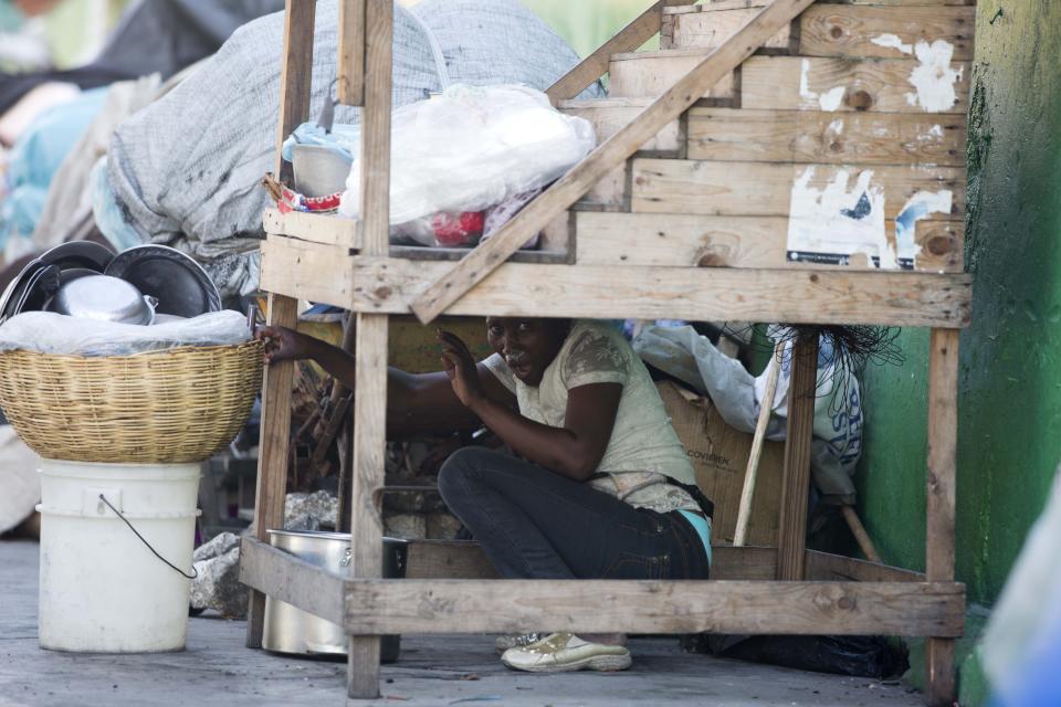 A street vendor hides during a clashes between protesters and national police officers as they demand the resignation of President Jovenel Moise and demanding to know how Petro Caribe funds have been used by the current and past administrations, in Port-au-Prince, Haiti, Saturday, Feb. 9, 2019. Much of the financial support to help Haiti rebuild after the 2010 earthquake comes from Venezuela's Petro Caribe fund, a 2005 pact that gives suppliers below-market financing for oil and is under the control of the central government. (AP Photo/Dieu Nalio Chery)