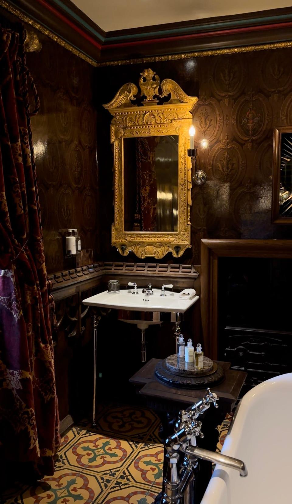 A twin sink with gold mirror and mahogany walls.