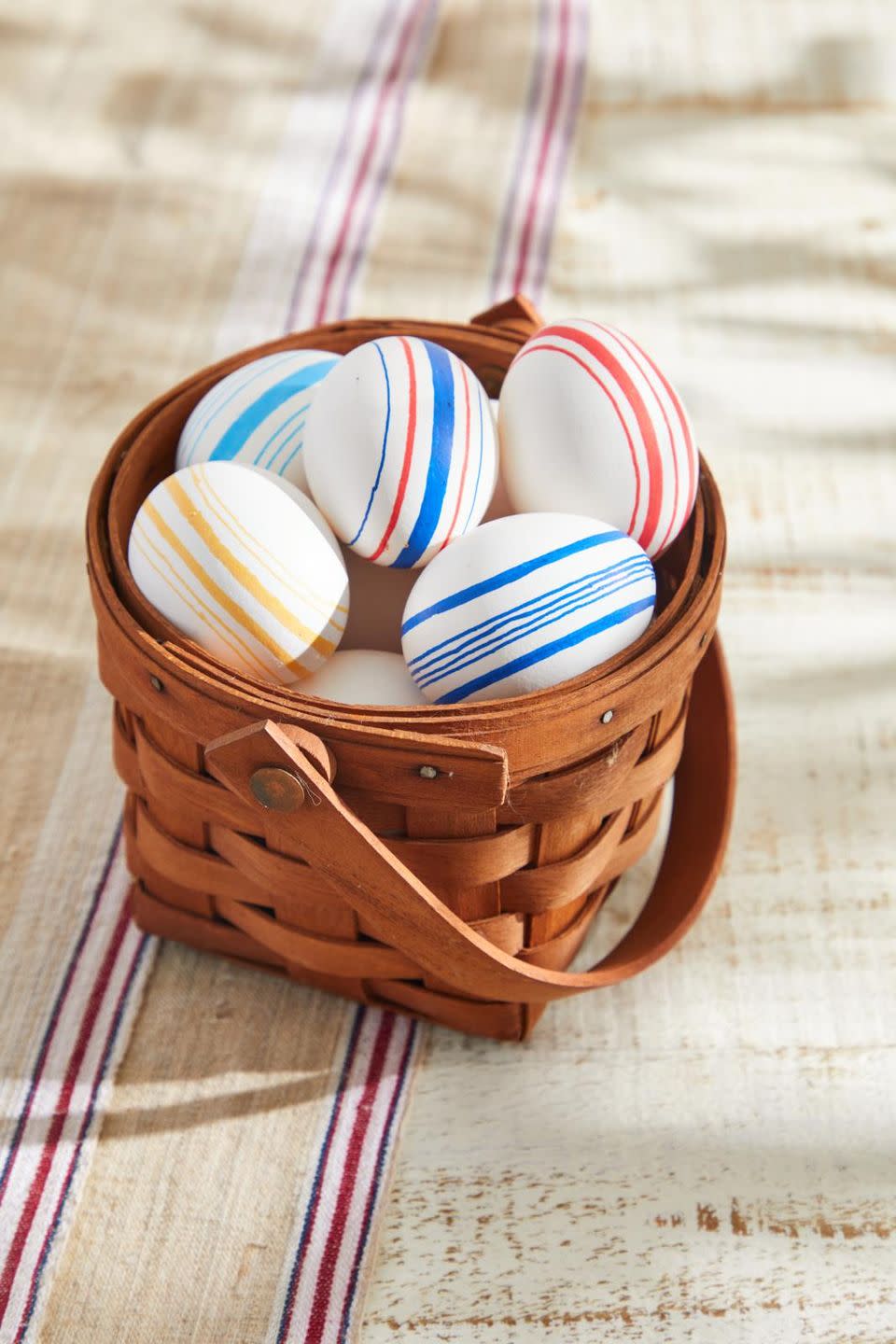 easter eggs decorated to look like vintage grain sack with striped on them set in an easter basket