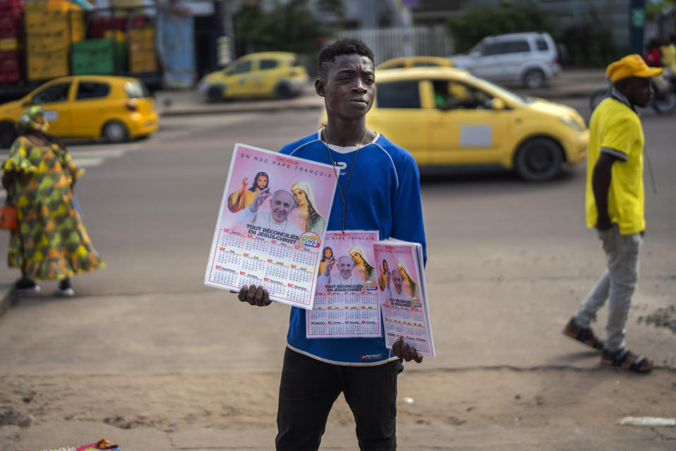 A young man sells calendars featuring Pope Francis outside the Cathedral Notre Dame du Congo in Kinshasa, Democratic Republic of the Congo, Sunday Jan. 29, 2023. Pope Francis will be in Congo and South Sudan for a six-day trip starting Jan, 31, hoping to bring comfort and encouragement to two countries that have been riven by poverty, conflicts and what he calls a "colonialist mentality" that has exploited Africa for centuries. (AP Photo/Jerome Delay)