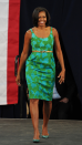 <p> Obama stood out in an eye-catching green and blue number during a campaign event held at a Florida high school in 2012. Her short-sleeved patterned Chris Benz knee-length dress featured a scooped neckline and was cinched in at the waist with a gold belt. She accessorised with dewy make-up and a pair of patent teal heels. </p>